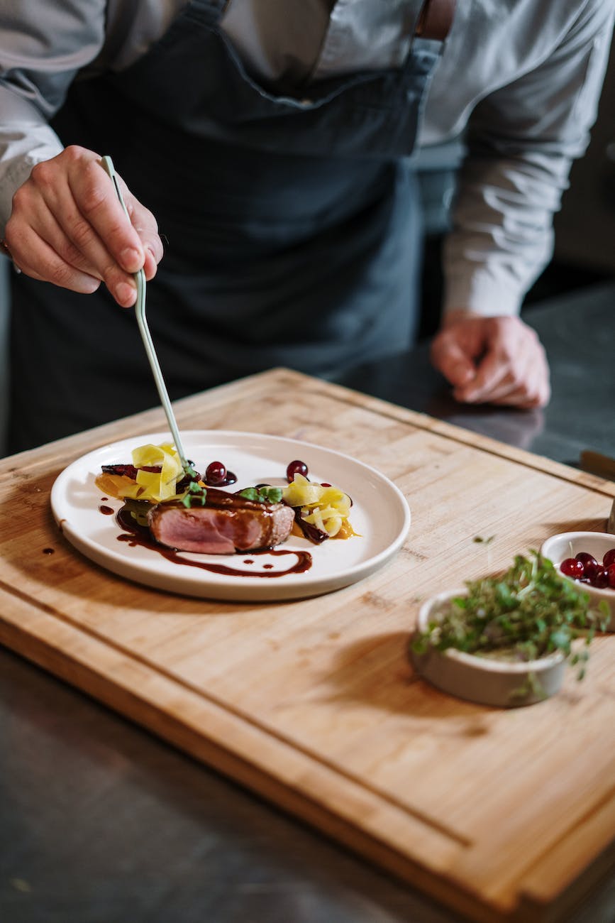 person holding silver fork and knife slicing vegetable on white ceramic plate